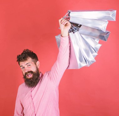 Sakal ve bıyık tutan alışveriş torbaları, kırmızı arka planı olan adam. Satış sezon indirimlerle alışveriş adam. Alışveriş kavramı. Mutlu yüz hipster bağımlısı alışveriş veya Alışverişkoliğin
