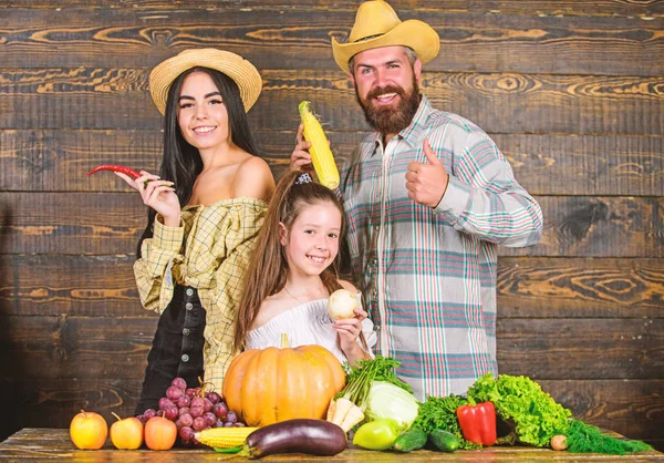 Family rustic style farmers at market with vegetables fruits and greenery. Family farm concept. Family farmers with harvest wooden background. Parents and daughter celebrate autumn harvest festival