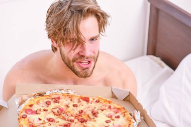 Evde yatakta lezzetli bir pizza yemek parlak bir apartman dairesinde öğrencidir. Ara diyet kavramı. Adam, kahvaltıda pizza seviyor. Yatak pizza.