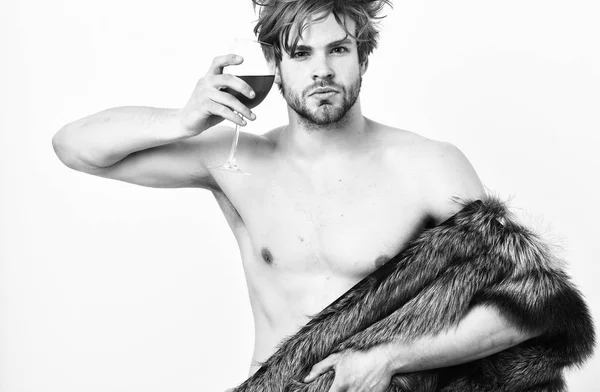男魅力的な豊富なポーズの裸の体に毛皮のコート豊富な選手は、彼の人生をお楽しみください。豊かさと贅沢なコンセプト。セクシーな眠そうな豊かなマッチョは乱れた髪は、白で隔離ワインを飲む。ファッションと情念 — ストック写真