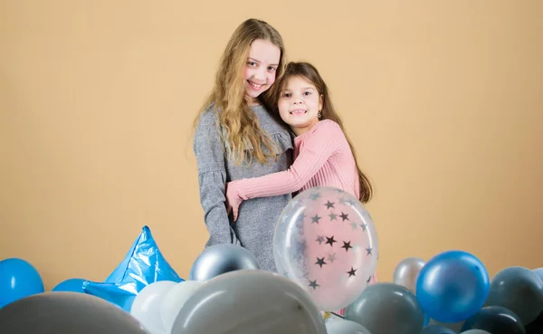 Sisterhood concept. Friendly relations siblings. Family love. Happy feeling love. Awesome to have loving sister. Sincere kids share tenderness and love. Girls hug near air balloons. Birthday party
