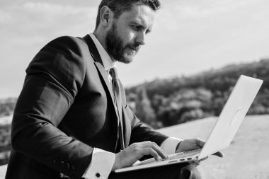 Oranları online satış ipuçları artırın. İşadamı sörf internet veya yanıt e-postalar ile dizüstü bilgisayar açık havada oturup süre. Nasıl yüksek yanıt oranları almak. Internet Pazarlama Yöneticisi mavi gökyüzü arka plan çalışır?