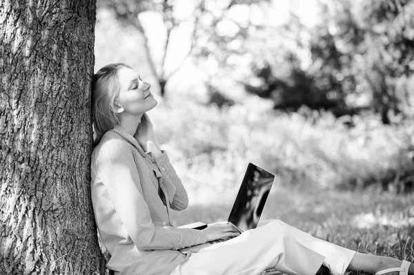 有笔记本电脑工作的妇女在户外瘦树。分钟放松。教育技术和互联网概念。女孩工作与笔记本电脑在公园坐在草地上。自然环境办公室。户外工作福利 — 图库照片