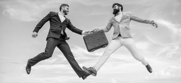 Case with raise your business. Successful transaction between businessmen. Briefcase handover in heaven blue sky background. Easy deal business. Businessmen jump fly mid air while hold briefcase