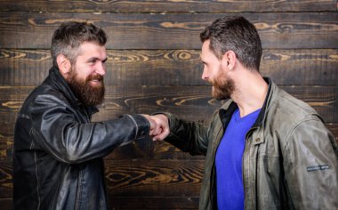 Acımasız sakallı erkekler tokalaşırken deri ceket giyer. Güçlü el sıkışma. Dostluk vahşi adamlardan. İş anlaşması onaylandı. Karşılıklı jest anlamına gelir. El sıkışma başarılı anlaşma sembolü. Kabul etmiş