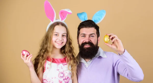 Looking for egg. Family of father and daughter smiling in Easter bunny ears. Happy family. Family celebrating Easter. Happy father and child with colored Easter eggs. Family at annual Easter egg hunt