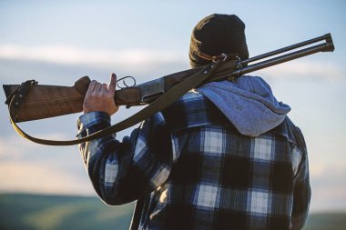 Avcı tüfeği silah omuz arka görünümü üzerinde taşırlar. Adam avcısı eğlence avcılık harcamak. Adam acımasız adam hakem şapka doğa arka planda. Avcılık erkeksi hobi eğlence kavramı. Vahşet ve erkeklik