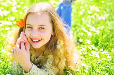 Çimen, grassplot arka plan üzerinde yatan kız. Çocuk çayır çiçeklerle yatarken bahar güneşli günü tadını çıkarın. Mevsimlik Anti kavramı. Kırmızı lale çiçek kız mutlu yüz tutan, aroma zevk