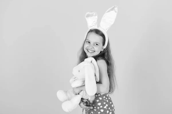 Barnet ler med bunny öron pannband. Påsk och våren firande. Barndom, ungdom och tillväxt. Glad tjej håller kanin leksak på rosa bakgrund. Fertilitet och nytt liv koncept, kopiera spac — Stockfoto