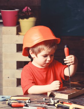 Çocuk Oluşturucusu'nu veya repairer oynamak, aletlerle çalışırız. Turuncu baret veya kask, çalışma odası arka plan çocuk evlat. Çocukluk kavramı. Gelecekteki kariyer mimarisi veya bina hakkında rüya çocuk
