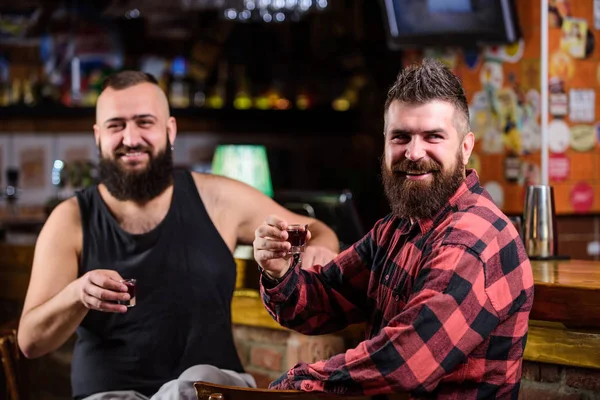 Hombres borrachos relajándose en el pub divirtiéndose. Bebidas alcohólicas fuertes. Viernes relajarse en el pub. Amigos relajándose en el pub. Concepto de salud. Hipster brutal barbudo hombre beber alcohol con amigo en bar mostrador — Foto de Stock