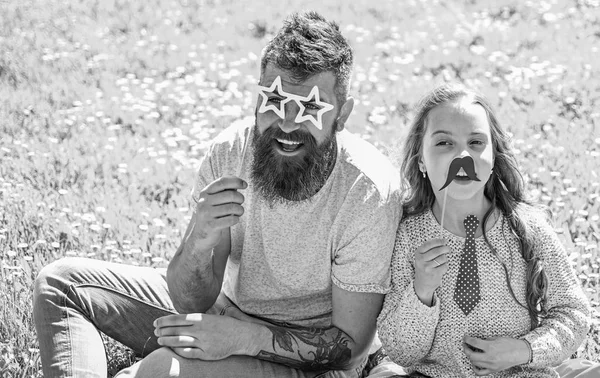 Concepto de mejores amigos. Papá y su hija se sientan en la hierba en Grassplot, fondo verde. Niño y padre posando con gafas, bigote y atributos de cabina de fotos de corbata. Familia pasar el ocio al aire libre — Foto de Stock