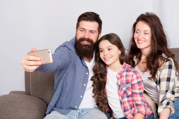 Rodina společně strávit víkend. Použijte smartphone pro selfie. Přátelská rodina baví spolu. Máma táta a dcera relaxační na gauči. Rodina, pózuje pro fotografie. Zachyťte šťastné okamžiky. Rodinné selfie — Stock fotografie