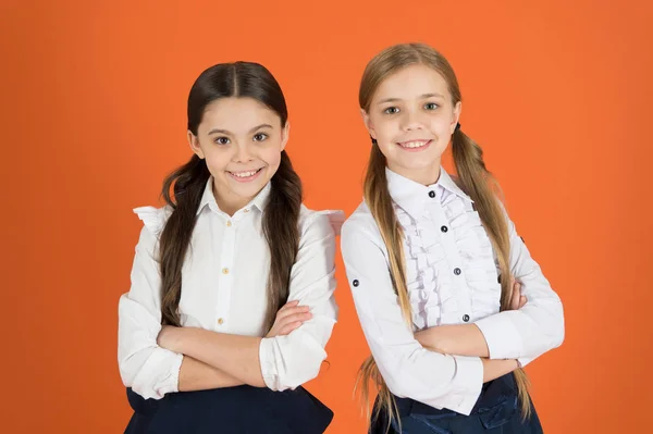 Mantener los brazos cruzados. Los niños de la escuela con una mirada hacia adelante de moda. Colegialas lindas. Niñas usando uniforme escolar. Chicas elegantes en coletas vestidas para la escuela. Volver al estilo de moda escolar —  Fotos de Stock