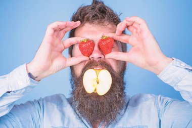 Meyve doldurma. Hipster sürpriz doldurma meyve tadını çıkarın. Adam doldurulmuş elma. Adam yakışıklı hipster uzun sakal elma tutun çilek yiyin. Apple ağız sakallı hippi çilek her iki elinde tutar.