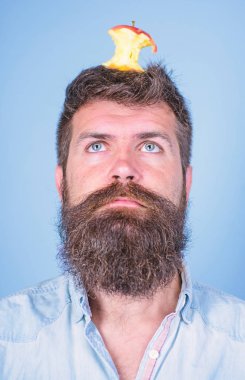 Adam yakışıklı hipster uzun sakal neredeyse kafasına elma güdük hedef olarak yem. Hipster sürpriz elma güdük hedef üzerinde kafa mavi arka plan, yüz kadar yakın. Kilo kaybı gol. Canlı hedef kavramı