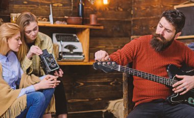Müzisyen trendy hipster sakal ve bıyık gitar çalmak. Sakallı adam ayarlama müzik aleti. Anne ve kızı Baba müzik, hobi kavramı beste yaparken eski video kamera ile ilgili