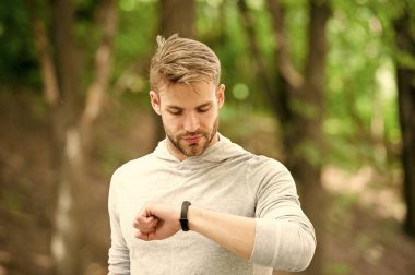 Adımölçer cihazıyla atletizm eğitimi. Meşgul yüz kontrolü yapan sporcu, spor takip cihazı, doğa geçmişi. Fitness takip cihazı ya da adım sayacı olan bir atlet. Spor aleti kavramı