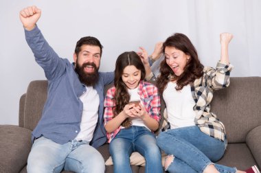 Aile birlikte hafta sonu geçirmek. Küçük kız kullanma smartphone ile çocuk anne. Dostu aile birlikte eğleniyor. Anne baba ve meşgul kızı kanepede rahatlatıcı. Aile eğlence. Ebeveyn tavsiyesi