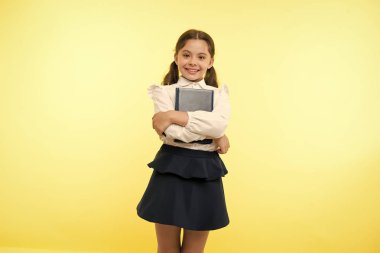 Mutlu kız kitap sarı arka plan üzerinde tutun. Küçük kız öğrenci ders kitabı gülümsemeyle. Moda kitap kurdu. İlk okul günü. Benim oyun öğreniyor