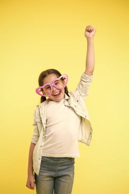 Hadi kutlayalım. Kalp şeklinde gözlük takan çocuk Sevgililer Günü 'nü kutlamak için neşeli bir çağrı yaptı. Kıvırcık saçlı kız Sevgililer Günü 'nü kutlayan gülen surat. Sevimli çocuk gülümsemesi sarı arka plan