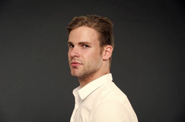 Güven ve erkeklik. Olarak, onun görünümünü kendine güvenen bir adam. Adam iyi bakımlı kıl ve saç modeli koyu arka plan ile. Maço emin katı yüz kapatın. Adam yakışıklı çekici beyaz gömlek