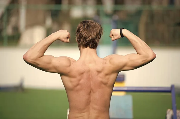 Dumni z jego kształt. Mężczyzna sportowiec szkolenia odkryty pokazuje jego mięśni pleców. Lekkoatletycznego mężczyzna pozowanie z mięśni. Lekkoatletka mięśni pleców trwa przerwa podczas wyczerpującym treningu. Trening sportowca odkryty — Zdjęcie stockowe