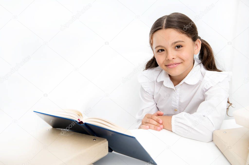 Being smart and cute. Small school child have literature lesson. Little girl reading lesson book in school. Schoolgirl reading school book at desk. Adorable pupil develop reading skills