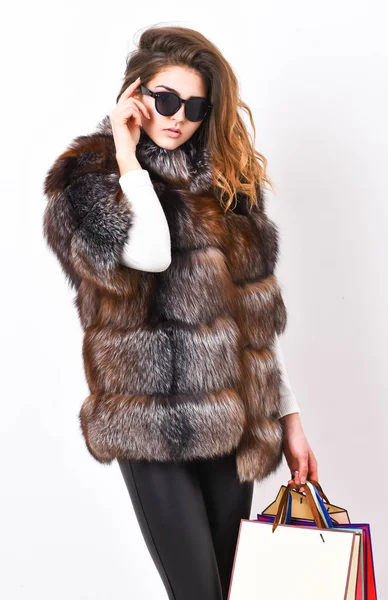 Woman shopping luxury boutique. Lady hold shopping bags. Discount and sale. Buy with discount on black friday. Shopping or birthday gift. Girl wear sunglasses and furry coat shopping white background