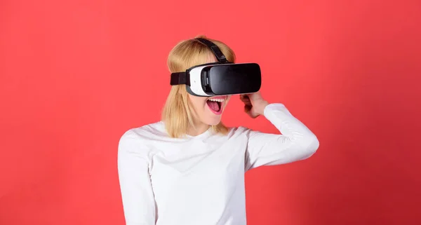 Retrato de mulher em uma blusa branca com óculos de realidade virtual na cabeça isolada em fundo vermelho. Jovem confiante ajustando seu fone de ouvido de realidade virtual e sorrindo . — Fotografia de Stock