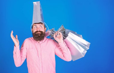 Uzun sakallı ve gümüş çanta eğleniyor başında olan adam. Alışveriş, moda ve satış konsepti yaparken şık sakallı hippi. Üzerinde mavi arka plan izole oynak bakışla pembe gömlekli sakallı adam