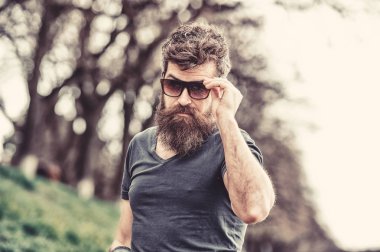 Adam ile şık güneş gözlüğü iyi görünüyor. Gözlüklü adam sakal ve bıyık giyer, ufuk arka plan. Hippi moda güneş gözlüğü ile kendine güvenen yüzünde. Göz koruma kavramı