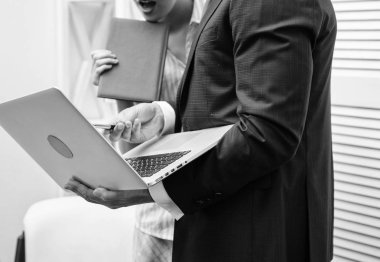 Kültür çalışıyorum. Mutlu yaratıcı ekibi ofiste çalışıyor. İki neşeli resmi kıyafeti holding dizüstü bilgisayar, kitap ve gençlerin bir şey birlikte çalışırken tartışıyor.