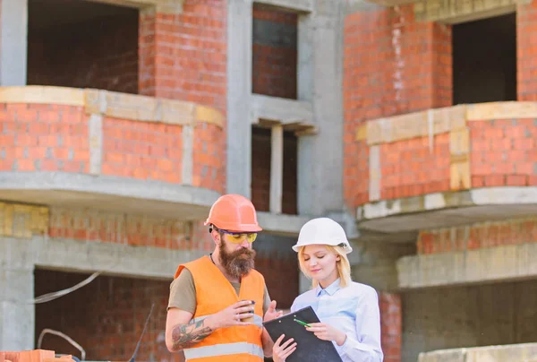 Concept de communication de l'équipe de construction. Relations entre les clients de la construction et les participants du secteur de la construction. Discuter du plan. Femme ingénieur et constructeur communiquent sur le chantier — Photo