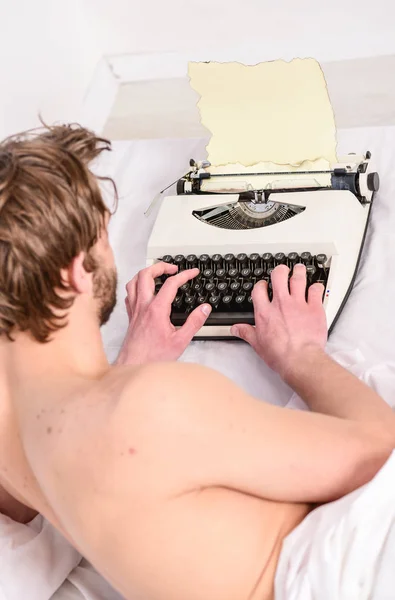 Spisovatel použít ruční psací stroj každodenní práci. Muž spisovatel ležela postel pracovat na nové knize. Spisovatel autor používá staré staromódní stroj namísto digitálních miniaplikace. Nový den přináší nové nápady. Ranní inspirace — Stock fotografie