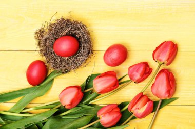 Sarı ahşap zemin üzerinde pembe ya da kırmızı renkli laleler.