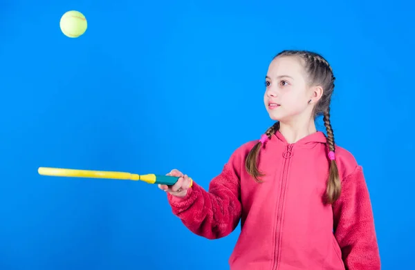 Орієнтований на м'яч. Дівчина чарівна дитина грає в теніс. Практикує тенісні навички та розважається. Спортсмен дитячої тенісної ракетки на синьому фоні. Активне дозвілля та хобі. Тенісні види спорту та розваги — стокове фото
