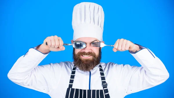 Conceito de processo de cozinha. Vamos experimentar o prato. Chef faminto pronto para experimentar comida. Está na hora de provar. Chef feliz sorrindo cara segurar colher e garfo. Homem bonito com barba segura utensílios de cozinha no fundo azul — Fotografia de Stock