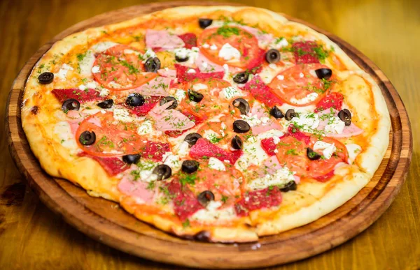 Pizza served with dill. Delicious hot pizza on wooden board plate. Food delivery service. Pizza with tomatoes black olives and ham. Take away food concept. Pizzeria restaurant. Italian pizza concept — Stock Photo, Image