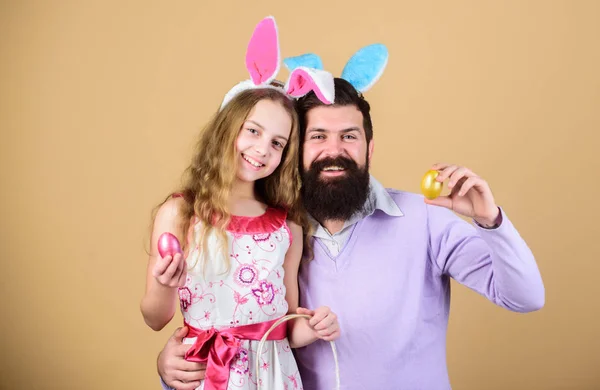 The first eggs. Family celebrating Easter. Happy family. Happy father and child with colored Easter eggs. Family of father and daughter smiling in Easter bunny ears. Family at annual Easter egg hunt