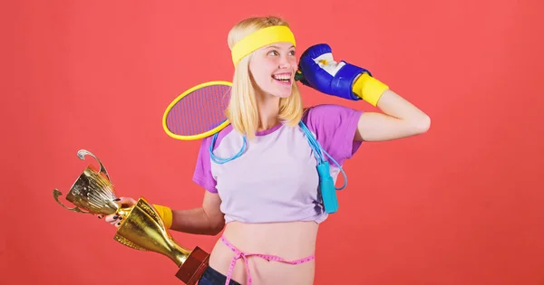 Desporto para todos os dias. Como ficar em forma para sempre. Loja de equipamentos desportivos. Variedade de lojas de desporto. Menina alegre bem sucedida mulher moderna segurar cálice dourado de campeão de esporte e equipamento fundo vermelho — Fotografia de Stock