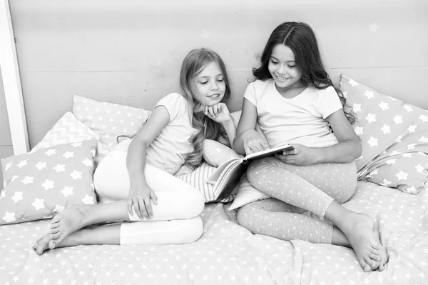 Τα παιδιά διαβάζουν βιβλίο στο κρεβάτι. Κορίτσια καλύτεροι φίλοι διαβάσει παραμύθι πριν από τον ύπνο. Καλύτερα βιβλία για παιδιά. Ανάγνωση πριν από τον ύπνο μπορεί να βοηθήσει τον ύπνο καλύτερα τη νύχτα. Ιστορίες που κάθε παιδί πρέπει να διαβάσετε. Οικογενειακή παράδοση — Φωτογραφία Αρχείου