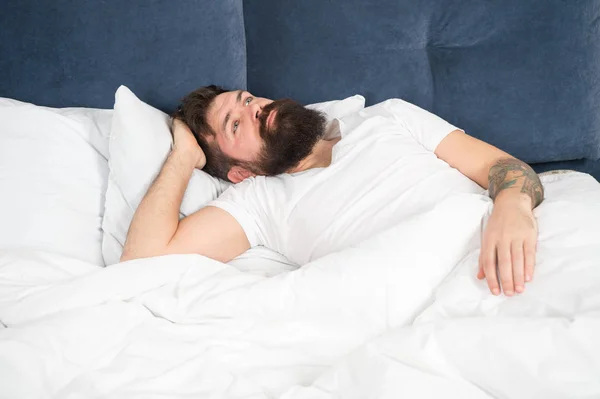 Homem barbudo hipster tendo problemas com o sono. O tipo deitado na cama tenta relaxar e adormecer. Técnicas de relaxamento. Violações do sono e da vigília. Noite sem dormir. Conceito de distúrbios do sono — Fotografia de Stock