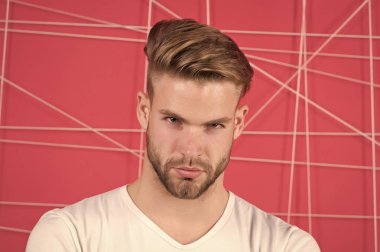 Katı konsantre yüzlü, pembe arka planda kıllı bir adam. Sakallı ve çekici bir adam. Erkeklik kavramı. Sakallı ya da traşsız adam yakışıklı ve bakımlı görünüyor.