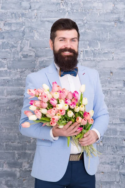 Romantic man with flowers. Romantic gift. Macho getting ready romantic date. Waiting for darling. Tulips for sweetheart. Man well groomed wear tuxedo bow tie hold flowers bouquet. Invite her dating