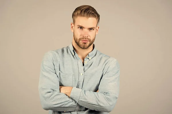Bearded man keep arms crossed on grey background. Macho with serious face. Tired after everyday work. Office dress code. Casual in style. Confidence and charisma. Young and handsome