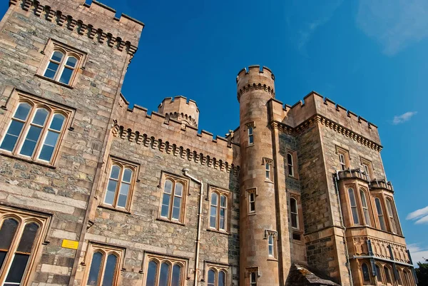 Castle building with towers on sunny blue sky. Lews Castle in Stornoway, United Kingdom. Historic architecture and design. Landmark and attraction. Summer vacation and wanderlust