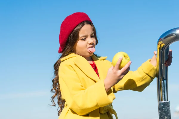 Eating this nutritious food is the hard part. Cute child hate eating fruit food. Little girl biting into sour green apple. Small baby holding unripe apple crop. Healthy food for a kid. Wholesome food