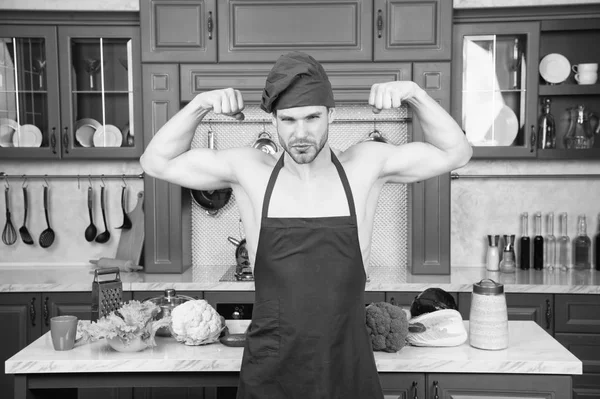 Sexy muscular chef in front of kitchen. Attractive chef ready to cook. Muscular chef posing in kitchen. Cook delicious recipe. Sexy macho cooking meal. Man attractive nude chef wear apron and hat — Stock Photo, Image