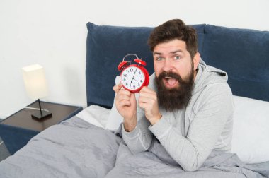 Sakallı hippi uykulu adam uyanıyor. Sağlıklı yaşam tarzı için günlük program. Sabah yine mutsuz. Çalar saat çalıyor. Sabah erken uyanma sorunu. Erken kalk. Erken kalkmak için bahşiş.